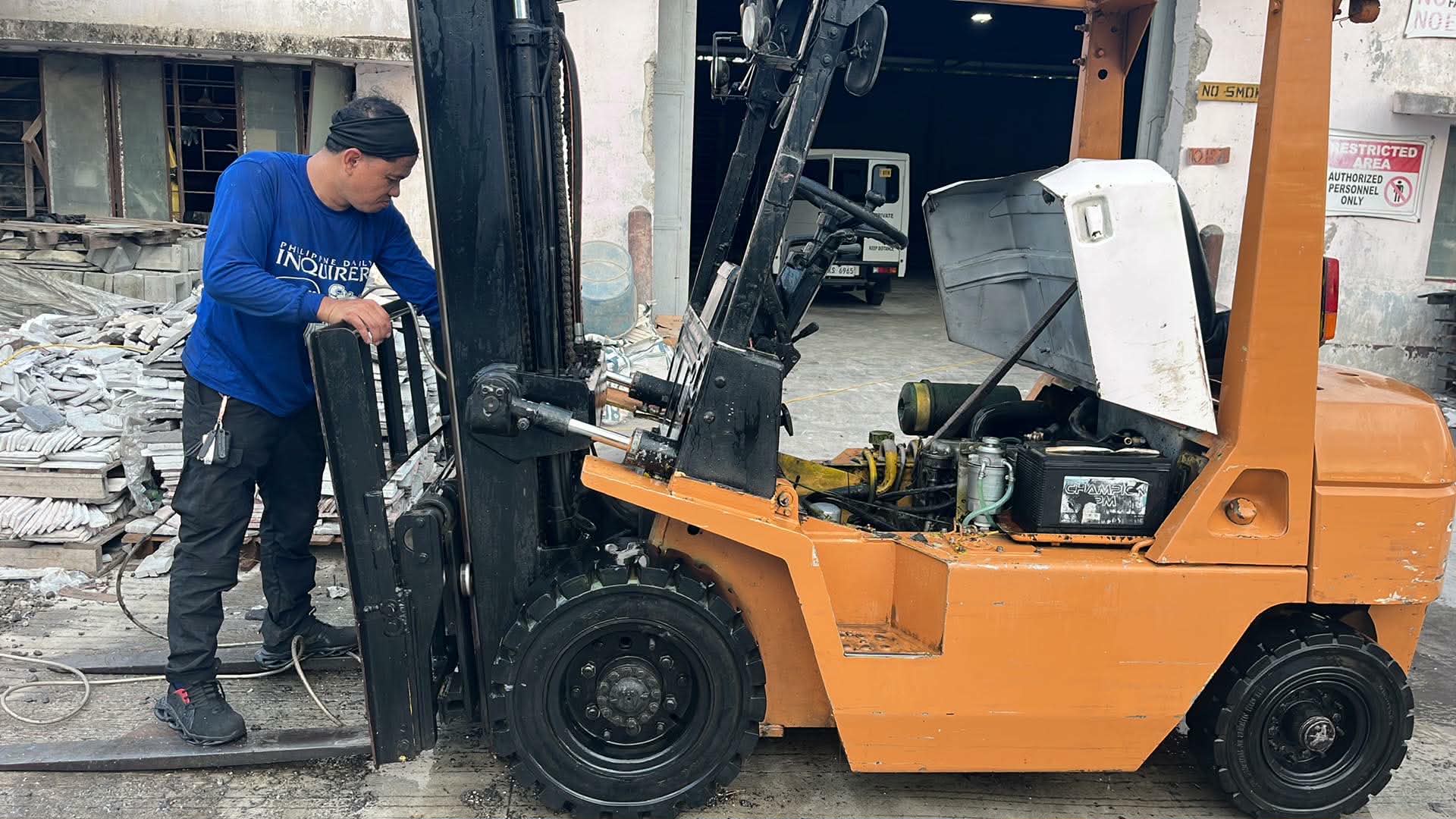 J.A.S technician servicing an orange forklift